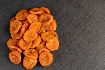 dried apricots from fresh apricots , dehydrated in the sun and without seeds, dried fruits on black slate