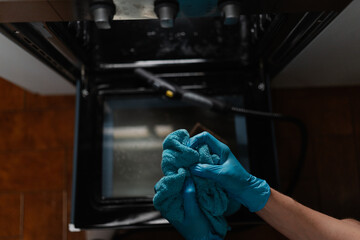 High-angle view of housekeeper male wearing blue gloves squeezing out wet rag after cleaning inside...
