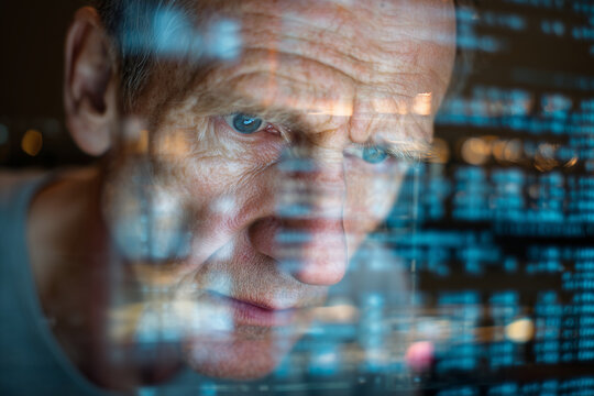 Focused man studies digital data with code reflecting on the man