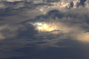 Dark, stormy clouds dominate the sky, with a central opening revealing an intense burst of light,...