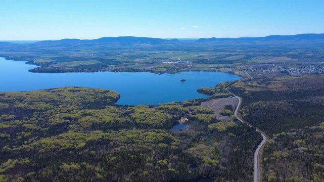 Panoramic aerial view of the Seigneurie du Lac Matap&eacute;dia, a vast expanse of tranquil water reflecting the blue sky surrounded by mountains and forests as far as the eye can see. Matapedia Valley.
