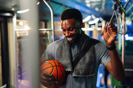 Smiling basketball player using smartphone on public transport at night