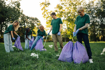 Volunteers collecting garbage in park using trash bags and pick up sticks