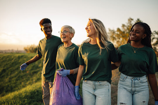 Group of volunteers collecting garbage in park are walking and talking
