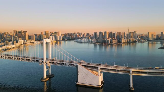 tokyo city skyline aerial shot drone at sunrise view of the waterfront with high office buildings seen from the sea with rainbow bridge in the foreground