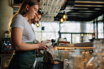 Bartenders polishing glasses at work getting ready to serve drinks