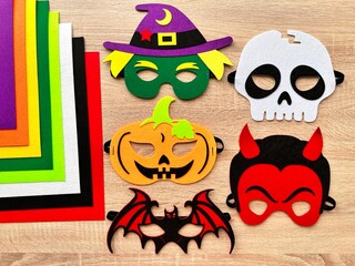 Halloween. DIY Felt Halloween Masks. Felt masks and felt sheets are lying on the table. Set of Various Masks, monsters, Pumpkin, Devil, Witch, Skeleton, Bat, DIY Toys, Dress Up Mask, Game Accessories.