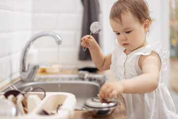 baby girl pretend play food toy, Child  washing dishes in a domestic kitchen