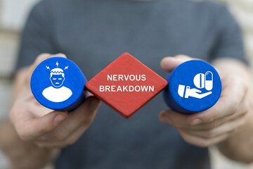 Exhausted person holding colored blocks with icons sees the inscription: NERVOUS BREAKDOWN. Nervous breakdown concept. Tired emotional person struggle with stress and overwork.