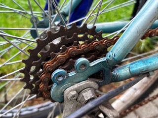 Close-up of a rusty bicycle chain and gear mechanism attached to a weathered blue frame with metal...