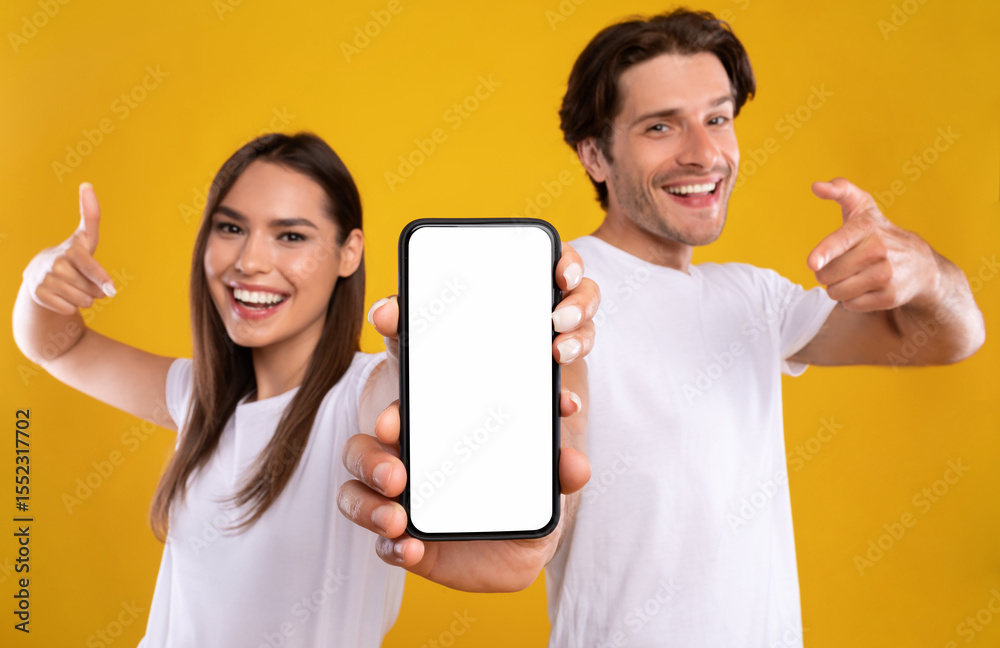 Poster use this new application. portrait of cheerful millennial couple pointing at smartphone with white s