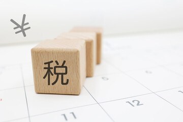 税金の納付期限や確定申告を意識させるカレンダーとブロックの構図