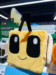 Naklejka premium Smiling square-shaped stuffed Minecraft character toy on store shelf under bright lighting