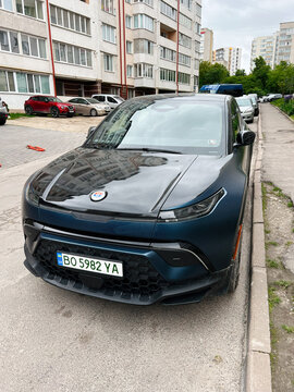 Modern blue Fisker Ocean SUV parked in urban residential area on a clear day