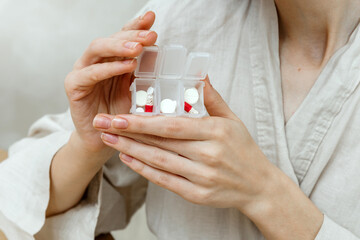 Woman holds pill organizers filled with various nutritional supplements for health