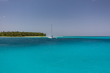 A beautiful tropical seascape taken in the Dominican Republic. A white sailboat glides across...