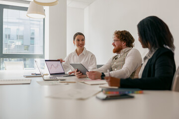 A diverse team collaborates in a bright office, using various devices for engaging discussions and...