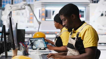African american technician evaluates renewable energy metrics at pc station, using advanced...