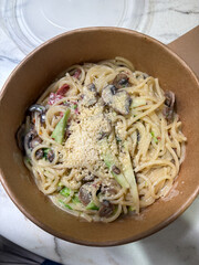 A bowl of mushroom spaghetti with cheese.