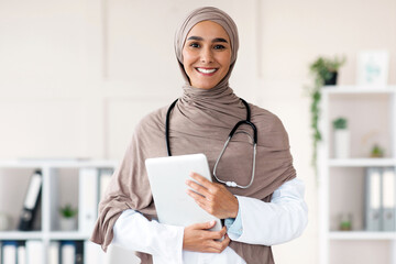 Modern technologies in healthcare concept. Happy female doctor in hijab posing with digital tablet...