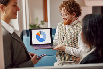 A dynamic and engaged team is showcasing and analyzing important data on a laptop in a...