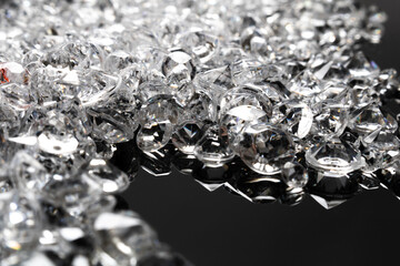 Scattered Cut Diamonds on Reflective Black Surface with Sparkling Highlights and Varied Shapes