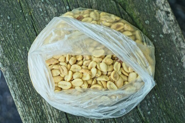 pile of brown roasted peanuts in clear plastic bag on grey table