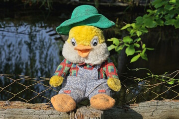 one big colorful plush toy duck stands on a gray table on a summer street