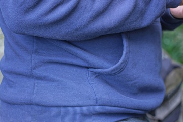 part of a blue autumn jacket on a man from an open pocket on a city street