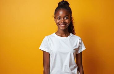 Smiling teenage girl wearing white t-shirt against yellow background. Young african american model, happy face, joyful smile. Casual fashion, studio shot, perfect for mockup design or apparel ad.