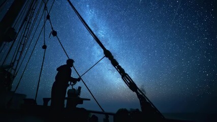 The silhouette of a ships mast against a backdrop of a vast starry sky a crew member silhouetted as they adjust the sextant in hand with constellations shining brightly above hinting