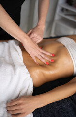 Masseuse applying massage oil on woman's abdomen