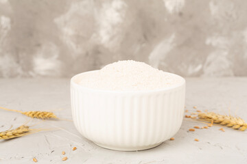 Bowl with spelt flour on concrete background