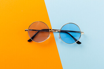 Blue sunglasses on color background, top view