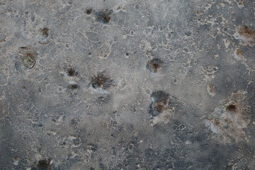 An abstract close-up photograph of a grey surface heavily scarred with bullet and shrapnel holes from the Second World War in Berlin, Germany.