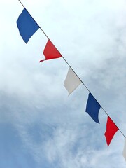 colorful flags in red, white, and blue hang across sky as clouds drift by, adding festive touch to...