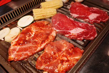 Raw ingredients are laid out on a tabletop grill, ready for a Korean BBQ or Japanese Yakiniku meal.