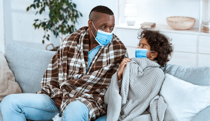 Coronavirus health alert concept. Little girl with her African American grandfather wearing...