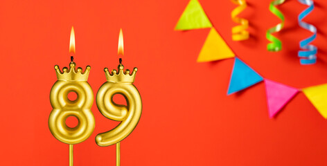 Number 89 candle - Birthday celebration on an orange background with pennants