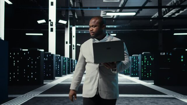 Data center system administrator coding on laptop, doing software updates. Server room IT specialist looking at device screen, optimizing infrastructure rackmounts configuration rigs, camera A