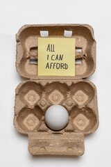 Food prices too high – single egg in cardboard carton with note about affordability
