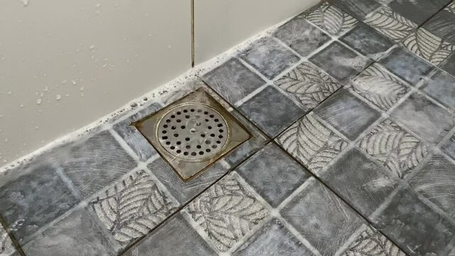 Water and foam flow to floor drain cover in bathroom