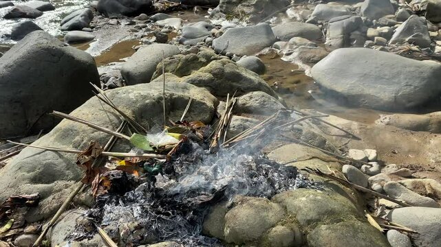 Burning waste on top of stones, close to river