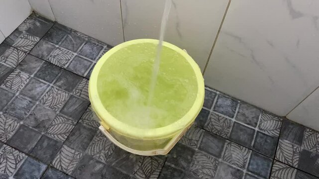 Overflow water on yellow plastic bucket at bathroom