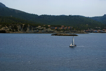 Scenic view of sailboat navigating sea water near Sa Mitjana islet and Sant Elm coast, Andratx,...