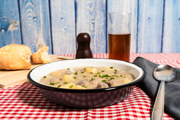 Traditional hungarian goulash soup served with bread and dark beer on a checkered tablecloth