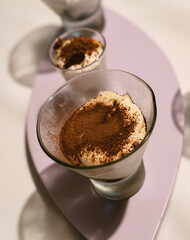Sweet table catering service. Closeup view of tiramisu cups with chocolate powder, in a light purple wooden board 