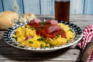 Delicious polenta with sausages, tomato sauce and chives, served on a beautiful plate