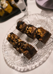 Sweet snacks in the gala. Closeup view of dark chocolate brownies with nuts, in a fancy dish