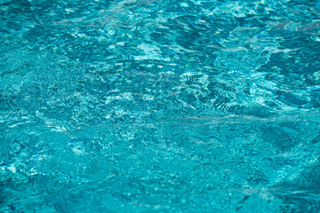 Ripple Water in swimming pool with sun reflection. Wavy water background.